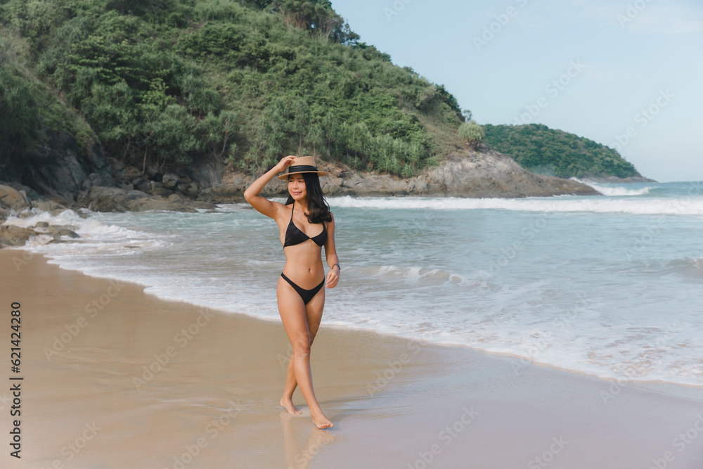 Φωτογραφία A woman wearing a bikini walks along the beach, experiencing pure bliss and serenity as she immerses herself in the coastal beauty