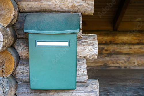 Mailbox with empty white label outside the wooden lean-to shelter photo