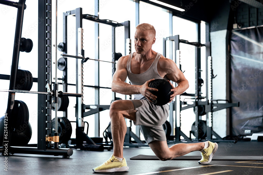 Fototapeta premium Fit and muscular man exercising with medicine ball at gym.