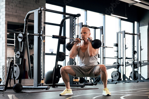 Squats with kettlebells exercise. Middle aged athlete doing functional workout at the gym.