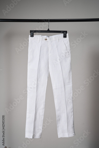 White classic pants on hanger mockup. School uniform, branding mock up. Studio shot, close up, grey background           