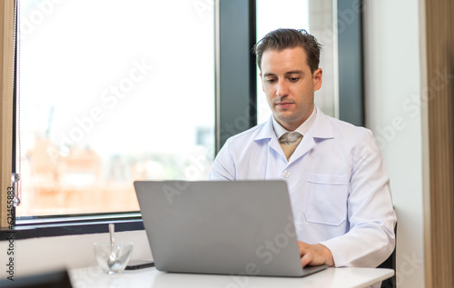 Man doctor wearing uniform with stethoscope working with laptop computer with virtual screen medical technology in hospital.healthcare technology and medicine