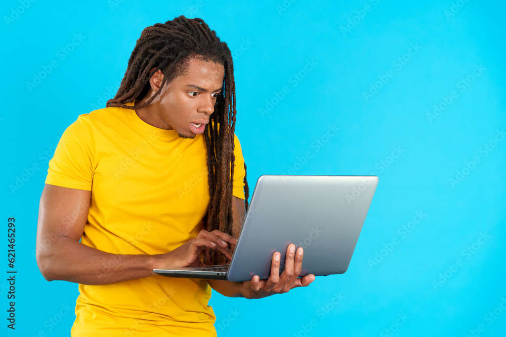 Surprised latin man with dreadlocks using a laptop Surprised latin man with dreadlocks using a laptop