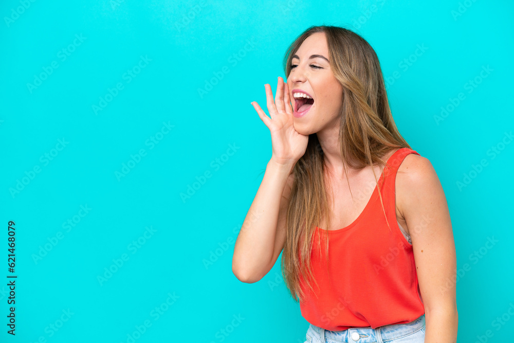 Young caucasian woman isolated on blue background shouting with mouth wide open to the side Young caucasian woman isolated on blue background shouting with mouth wide open to the side