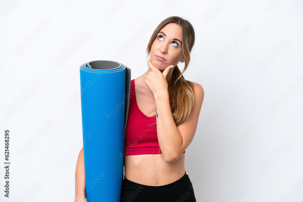 Young sport woman going to yoga classes while holding a mat isolated on white background having doubts Young sport woman going to yoga classes while holding a mat isolated on white background having doubts