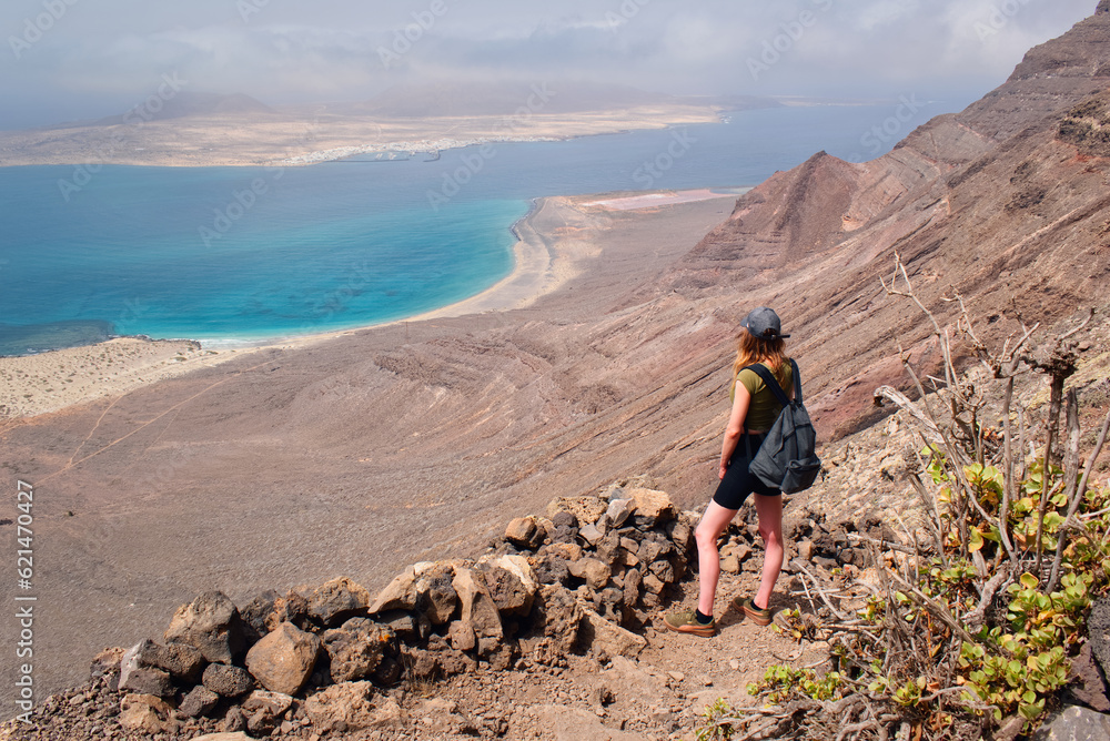 Beautiful young woman hiking to Del Risco beach at Lanzerote, Canary islands, travel and adventure concept, season and tourism