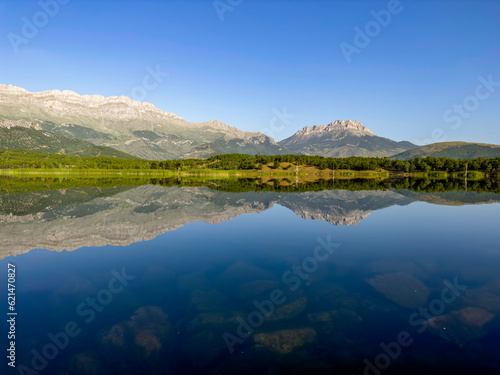 reflections of mountains and forest trees in the pond © emerald_media