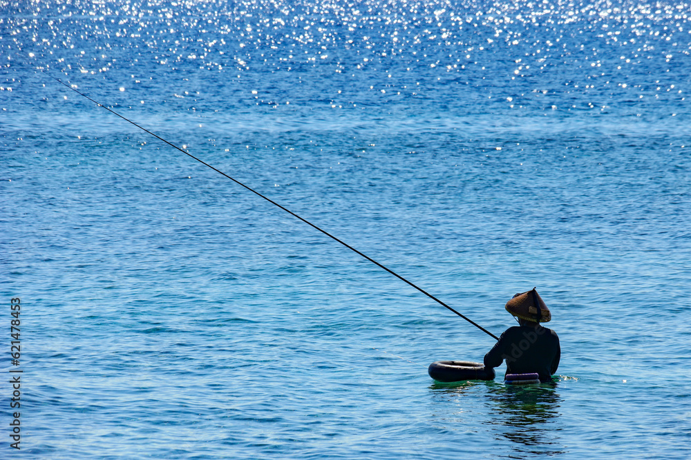 A local fisherman with his rod in the ocean on Gili Air, Lombok.
