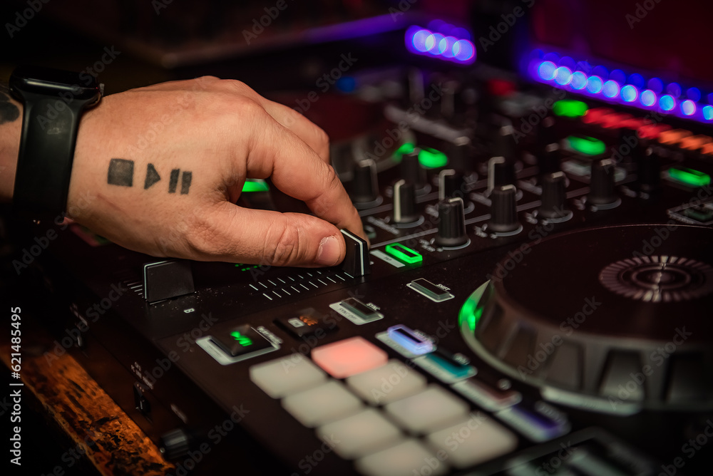 Close up of DJ hands controlling a music table in a night club.