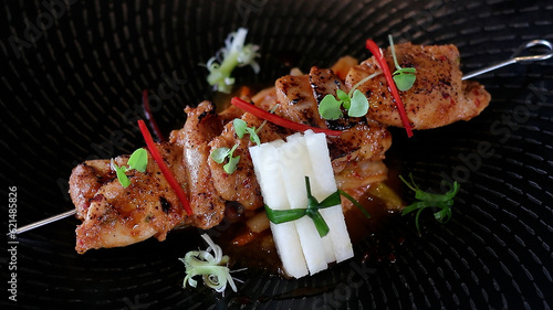 Spicy Korean grilled chicken skewer served with kimchi, spring onion and Asian pear. photo