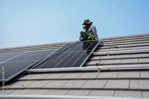 A technician is installing solar panels on the roof to use solar energy to power the building.