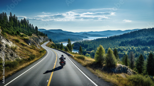 Road in mountains with motor bike biker driving, lake in background