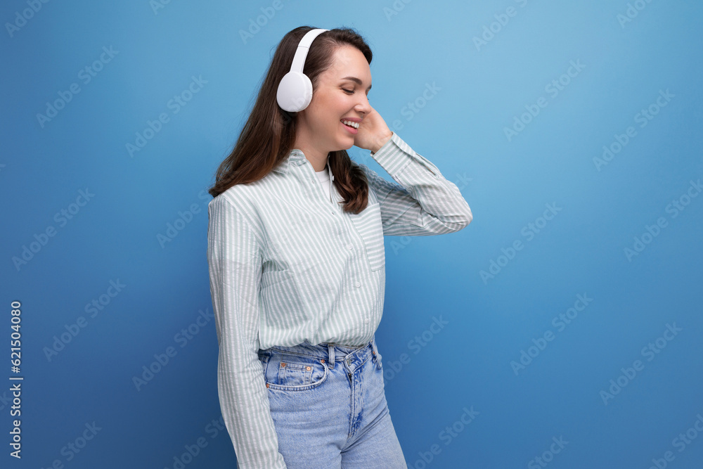 optimist energetic brunette young lady with hair below her shoulders listens to music with headphones optimist energetic brunette young lady with hair below her shoulders listens to music with headphones