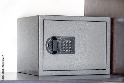 grey closed safe for storing money and documents with buttons on the shelf of the wardrobe in the hotel room