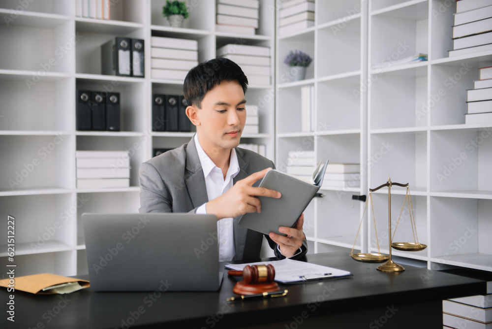 Naklejka premium Asian man lawyer reading legal book with gavel on table in office. justice and law ,attorney concept.