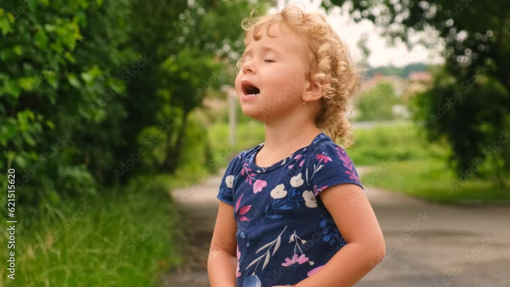 A child plays around and makes faces in the park. Selective focus. A child plays around and makes faces in the park. Selective focus.