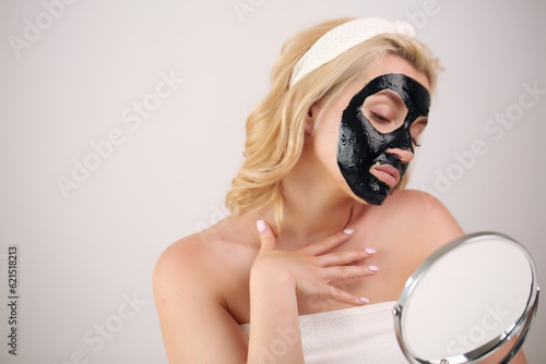 Woman face with black peeling mask on skin.applying cosmetic mask on face.