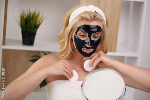 Happy girl applying facial mask - Young woman having skin care spa day - Beauty clean treatment day and cosmetology products concept