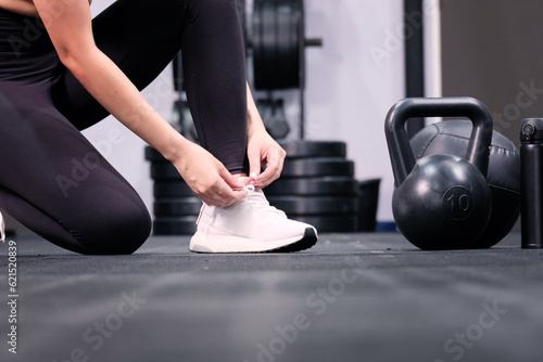 Young fitness woman tying shoelaces in gym fitness concept