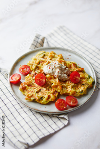 Snack waffles with bacon, cheddar cheese, spinach, sauce and cherry tomatoes on light background