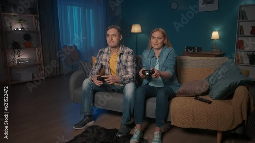 A woman and a man are playing a consular game with a game controller. The woman joyfully wins, points to herself, I am the BEST. The man is upset. Weekend leisure concept. photo