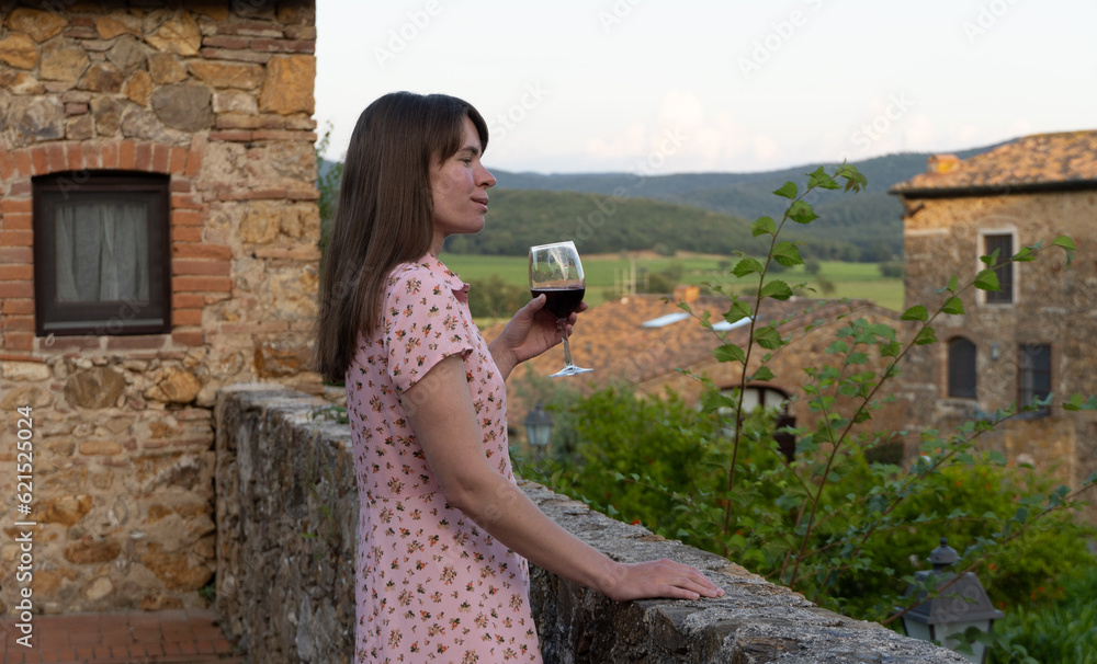 Tuscany, Italy. Young beautiful brunette woman drinking red wine in the patio of an old Italian villa