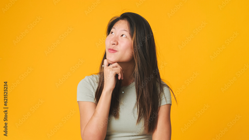 Girl in gray top looking at camera, smiling and flirting isolated on yellow background in studio Girl in gray top looking at camera, smiling and flirting isolated on yellow background in studio