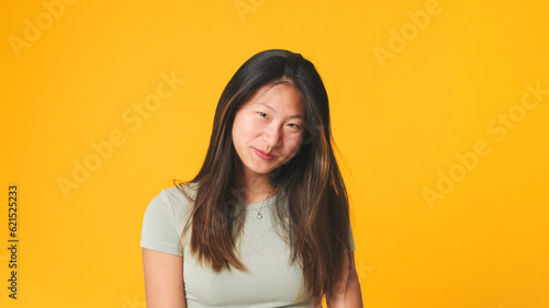 Girl in gray top looking at camera, smiling and flirting isolated on yellow background in studio © Andrii Nekrasov