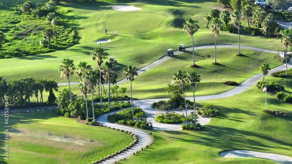 Aerial view of golfer driving golf cart on vast green golf course in sunny Florida. Active lifestyle of wealthy people Aerial view of golfer driving golf cart on vast green golf course in sunny Florida. Active lifestyle of wealthy people
