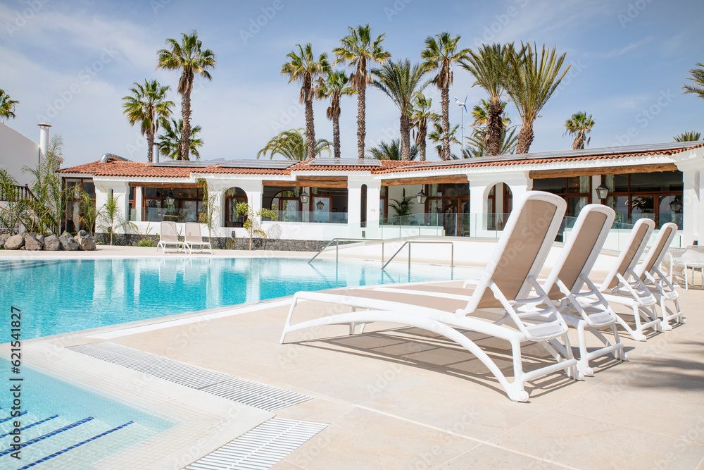 Clean and fresh resort swimming pool lined with comfortable sunbeds prepared for tourists to enjoy the summer vacation days at The Club, Amarilla Golf, Tenerife, Canary Islands, Spain 