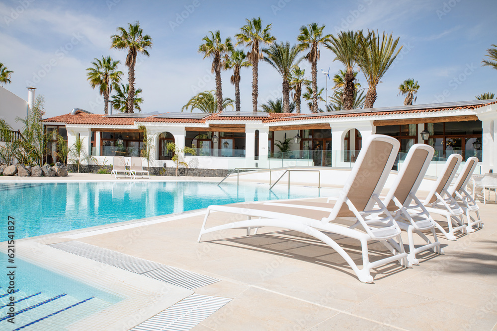 Clean and fresh resort swimming pool lined with comfortable sunbeds prepared for tourists to enjoy the summer vacation days at The Club, Amarilla Golf, Tenerife, Canary Islands, Spain Clean and fresh resort swimming pool lined with comfortable sunbeds prepared for tourists to enjoy the summer vacation days at The Club, Amarilla Golf, Tenerife, Canary Islands, Spain