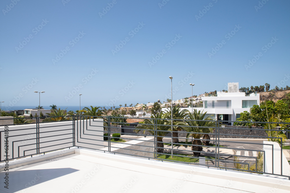 Ocean and neighborhood views from a spacious balcony with minimalist railing frame situated at the top floor of a modern property in the upscale village of La Caleta, Tenerife, Canary Islands, Spain Ocean and neighborhood views from a spacious balcony with minimalist railing frame situated at the top floor of a modern property in the upscale village of La Caleta, Tenerife, Canary Islands, Spain