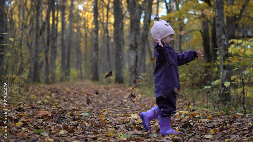 Adorable two years old girl twirl under falling leaves in autumn forest Adorable two years old girl twirl under falling leaves in autumn forest