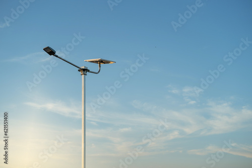 A modern street LED lighting pole.Public city light with solar panel powered on blue sky with clouds
