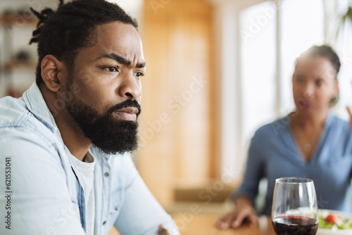 Close up of young African American man feeling sad while arguing with his wife at dining table