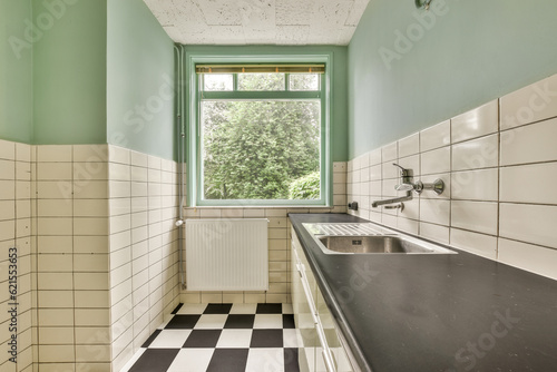 a kitchen with black and white checkered tiles on the floor in front of the window  looking out to the trees outside