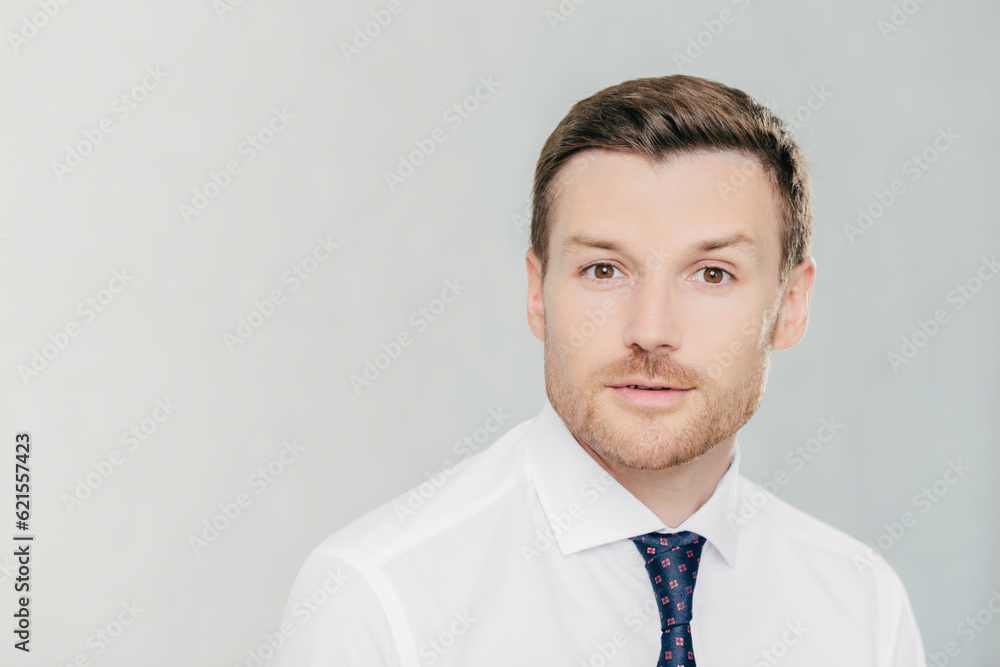 Attractive male freelancer works remotely, wears elegant white shirt with tie. Isolated on white studio wall. People, facial expressions, and work concept. Attractive male freelancer works remotely, wears elegant white shirt with tie. Isolated on white studio wall. People, facial expressions, and work concept.