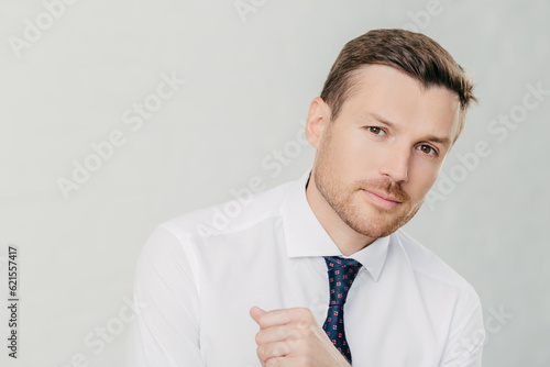 Handsome entrepreneur in white shirt looks at camera, listens attentively to interlocutor, talks business. Isolated on white background. photo