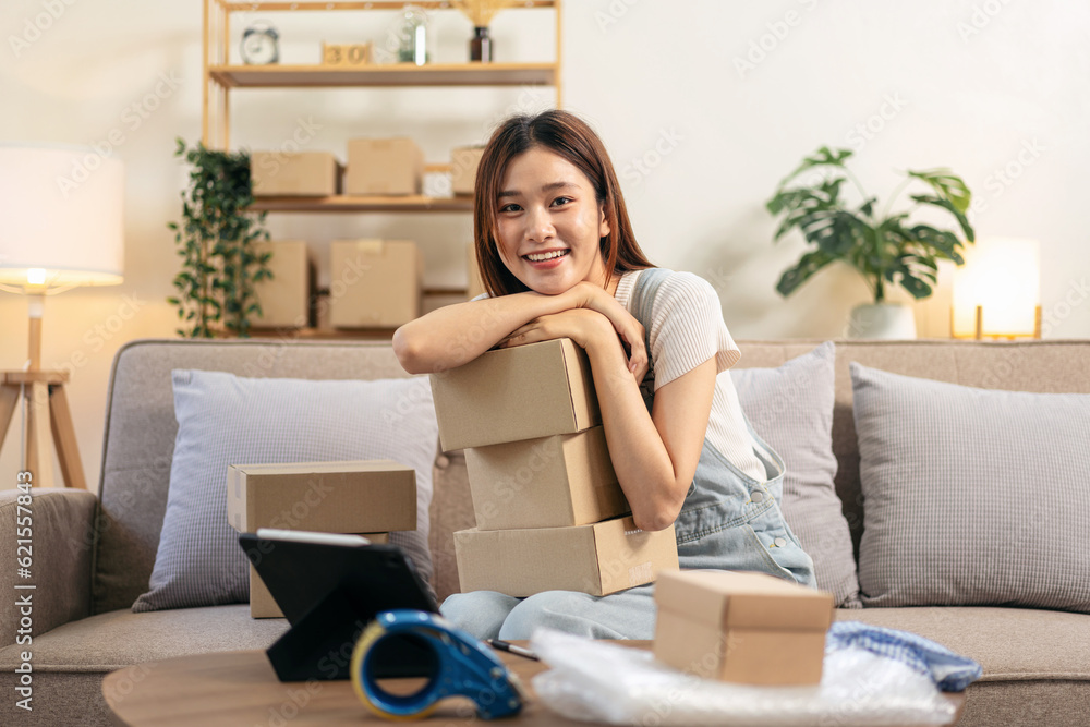 Young entrepreneur holding cardboard boxes and reading customer data on tablet to writing address Young entrepreneur holding cardboard boxes and reading customer data on tablet to writing address
