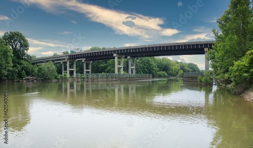 Highway bridge over muddy brown river with blue sky and clouds