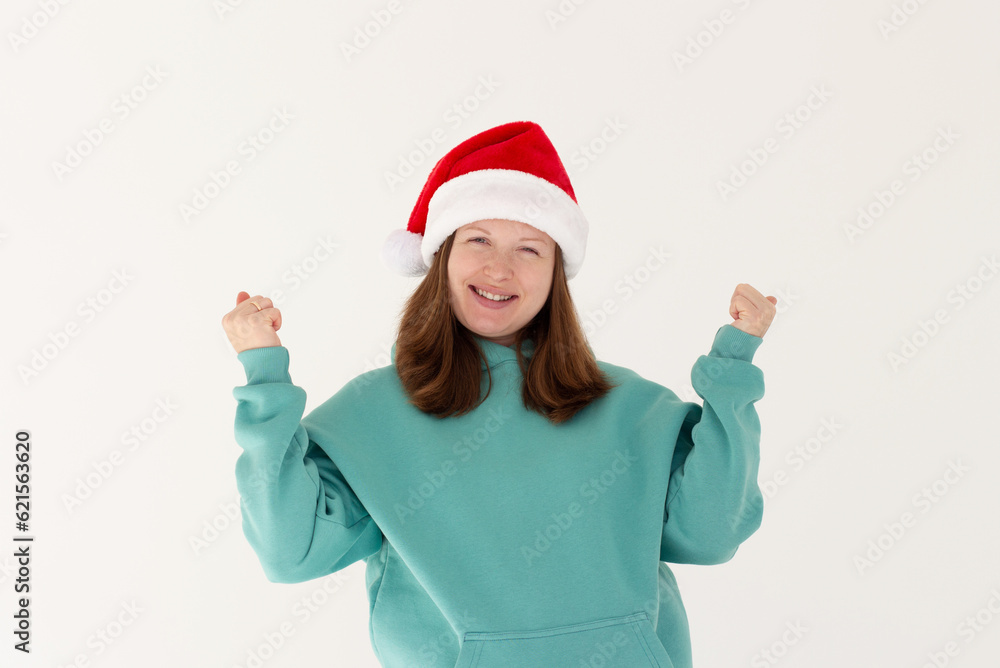 Excited young Santa girl in Christmas hat isolated on white background. Happy New Year end of year celebration holiday concept. Simulate copy space. Clenching fists like the winner. Excited young Santa girl in Christmas hat isolated on white background. Happy New Year end of year celebration holiday concept. Simulate copy space. Clenching fists like the winner.