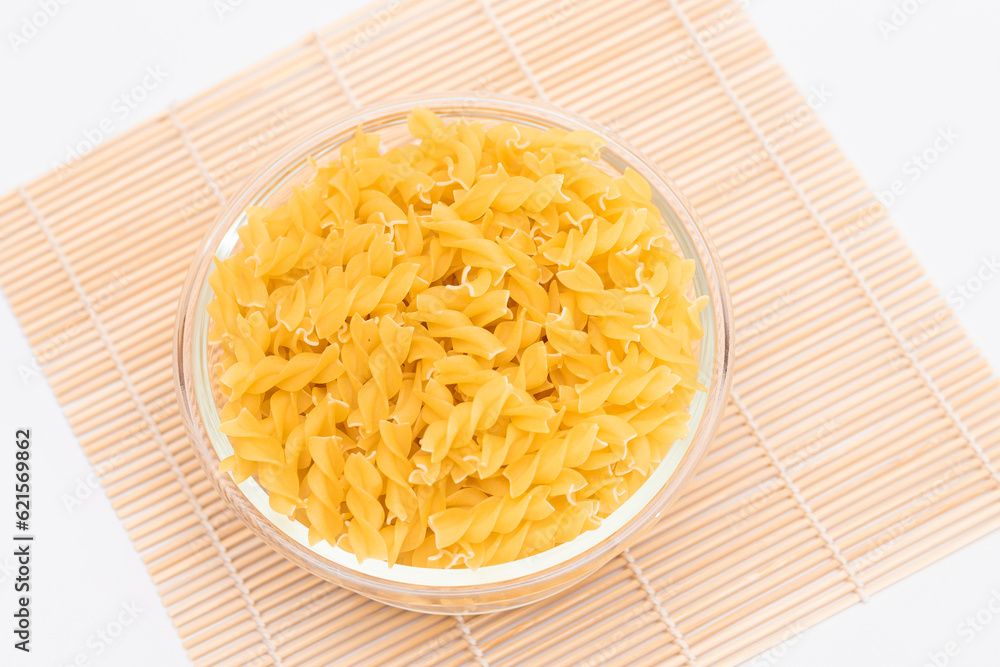 Uncooked Chifferi Rigati Pasta in Glass Jar on Bamboo Mat on White Background. Fat and Unhealthy Food. Classic Dry Macaroni. Italian Culture and Cuisine. Raw Pasta Uncooked Chifferi Rigati Pasta in Glass Jar on Bamboo Mat on White Background. Fat and Unhealthy Food. Classic Dry Macaroni. Italian Culture and Cuisine. Raw Pasta