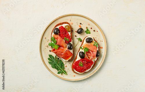 sandwiches with cheese and prosciutto, dried tomatoes and olives, breakfast on a plate,