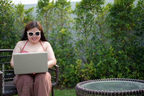 Portrait of Confident female asian sitting at poolside using laptop. © mojo_cp