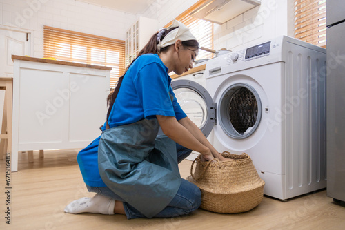 Young housewife doing laundry, drying, spinning with automatic washing machine.