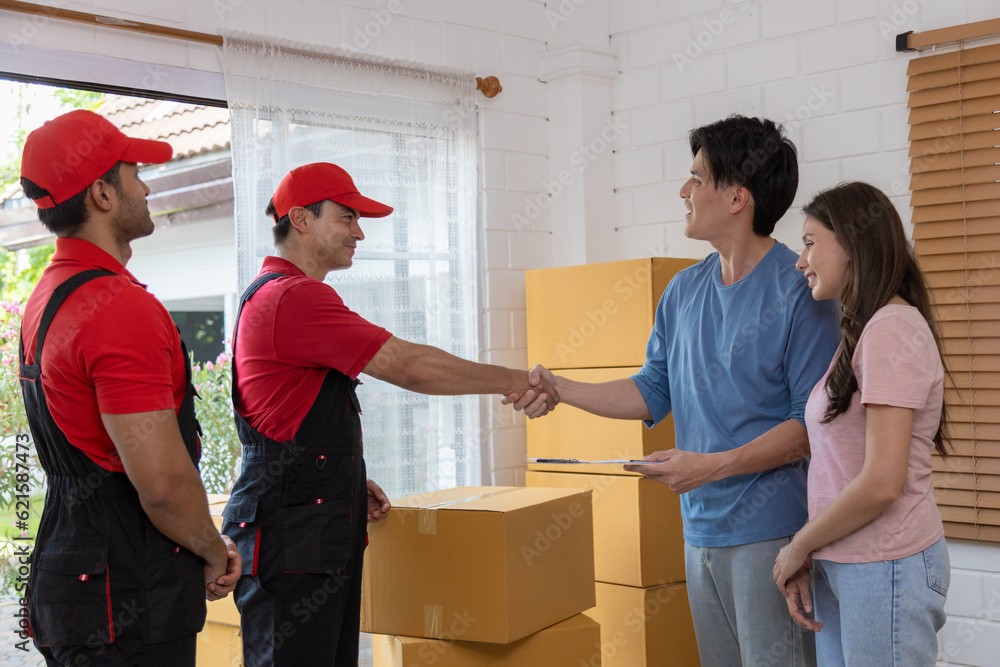 Young couple checks with two movers unloading boxes and furniture from a pickup truck
Young couple checks with two movers unloading boxes and furniture from a pickup truck