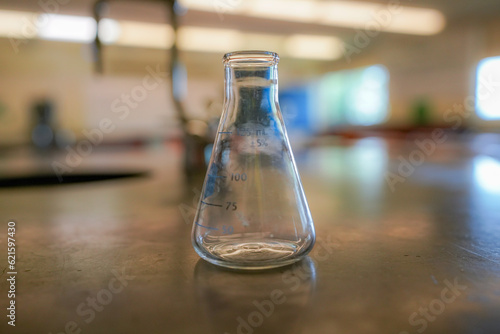flask on a black resin table with a high school science room background.