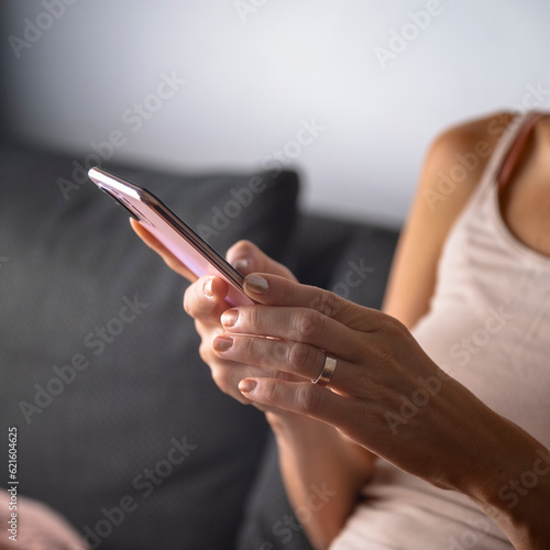 Closeup view of a woman on domestic sofa using her mobile phone