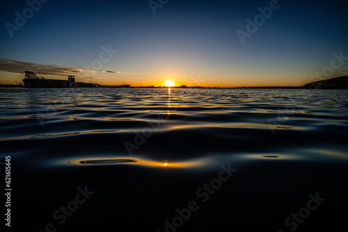 sun setting into horizon behind lake