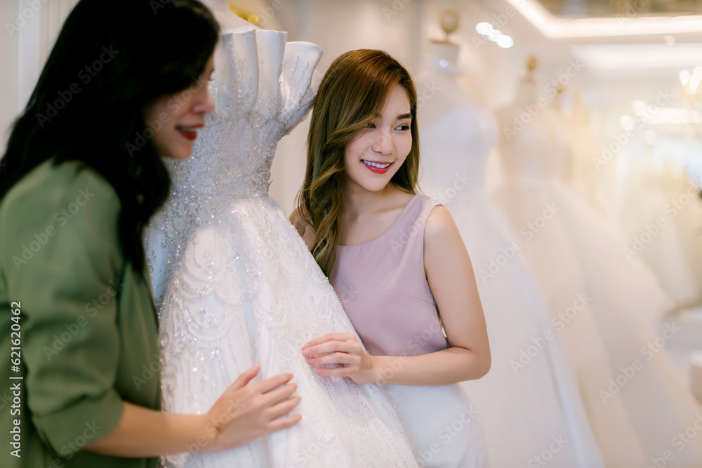 Naklejka premium Female bridal store owner work in wedding studio shop. Owner Of Bridal Wedding Dress Shop Work in shop. Designer woman working wedding dress in store..